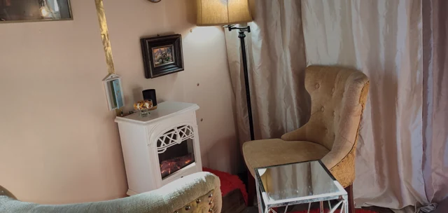 Cream armchairs, a floor lamp, small tables, and draped curtains.