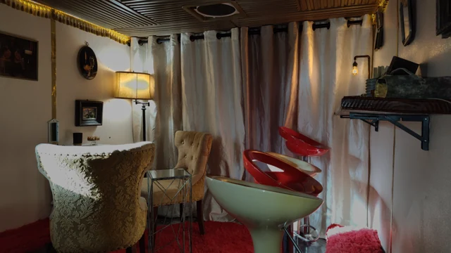Draped curtains, vintage seating, and warm lamp light.