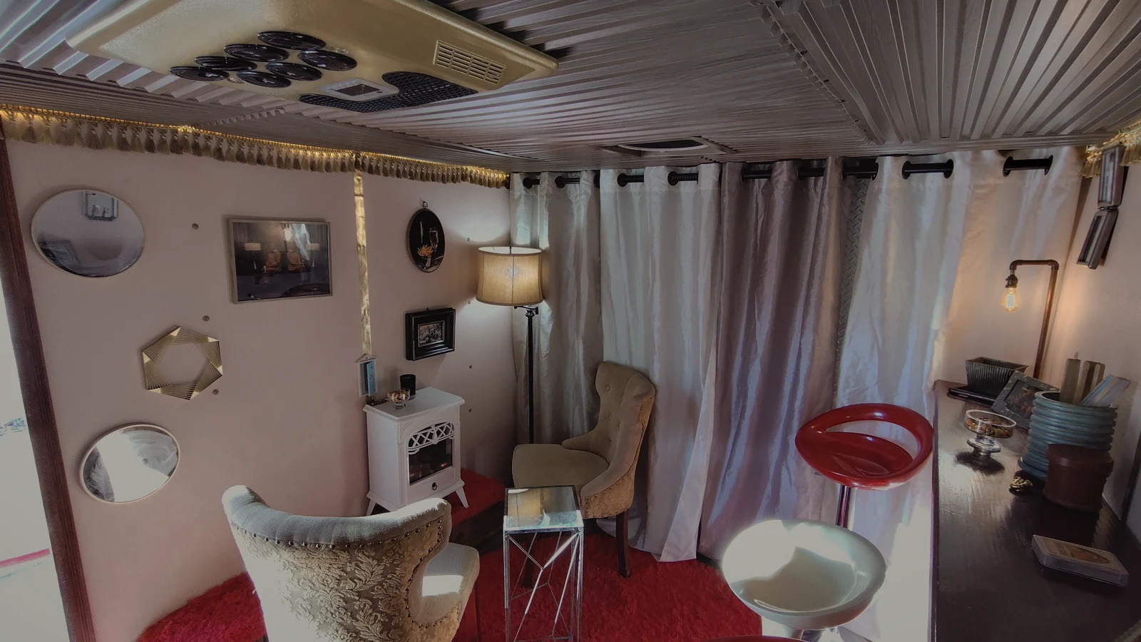 Inside the actual lounge: vintage armchairs, red shag rugs, draped curtains, and warm lamps.